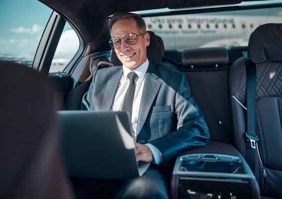 businessman smiles in his seat aboard a car rental